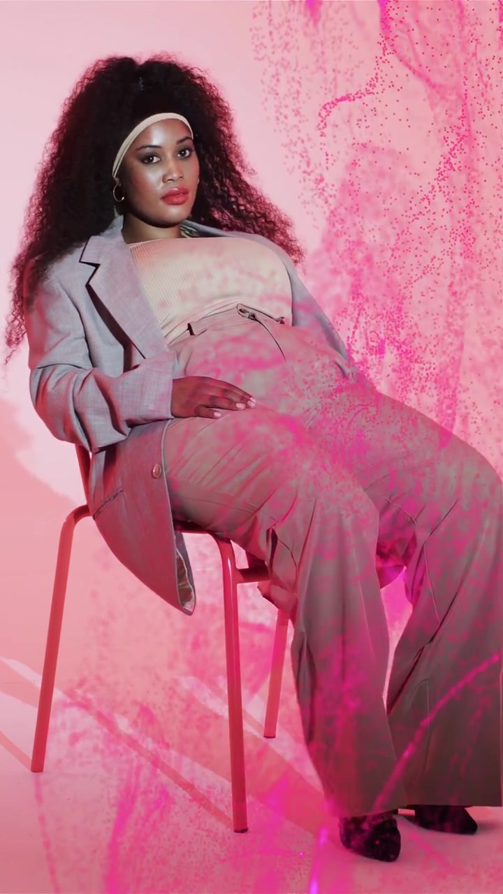 Vertical video: Beauty woman posing as pink veil entering causing sitting up opening blazer for ad