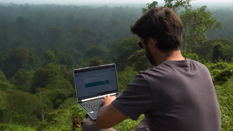 man working on a laptop in a forest