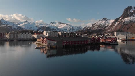 Aerial drone shot of a small sea town with big snowy mountains in the background