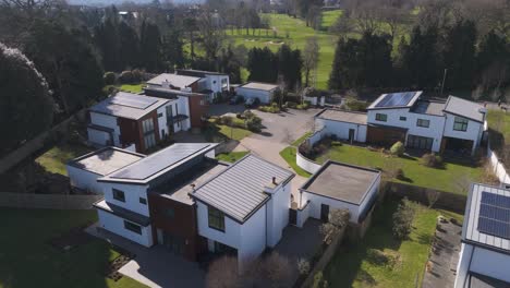 aerial of secluded cluster of layered cube homes with wood cladding, fenced gardens and rooftop panels set within mature greenery for discreet eco retreat