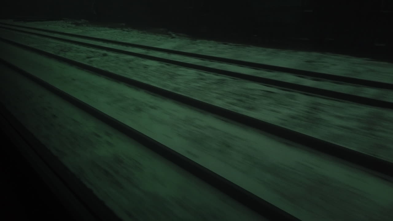 Passenger point of view looking out a train window at tracks passing by on an overcast winters day