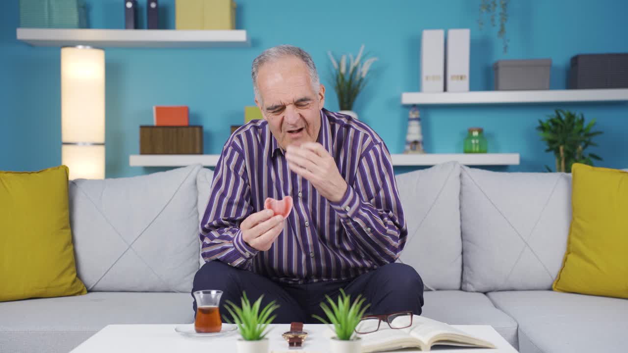 el anciano se pone sus prótesis en la boca.