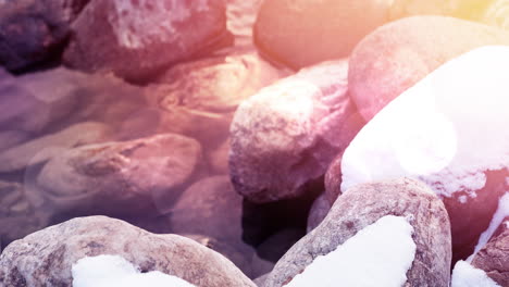 animation of stones in water during winter covered in snow and frost with light spots