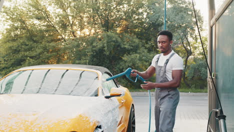 man washing a yellow convertible car at a car wash