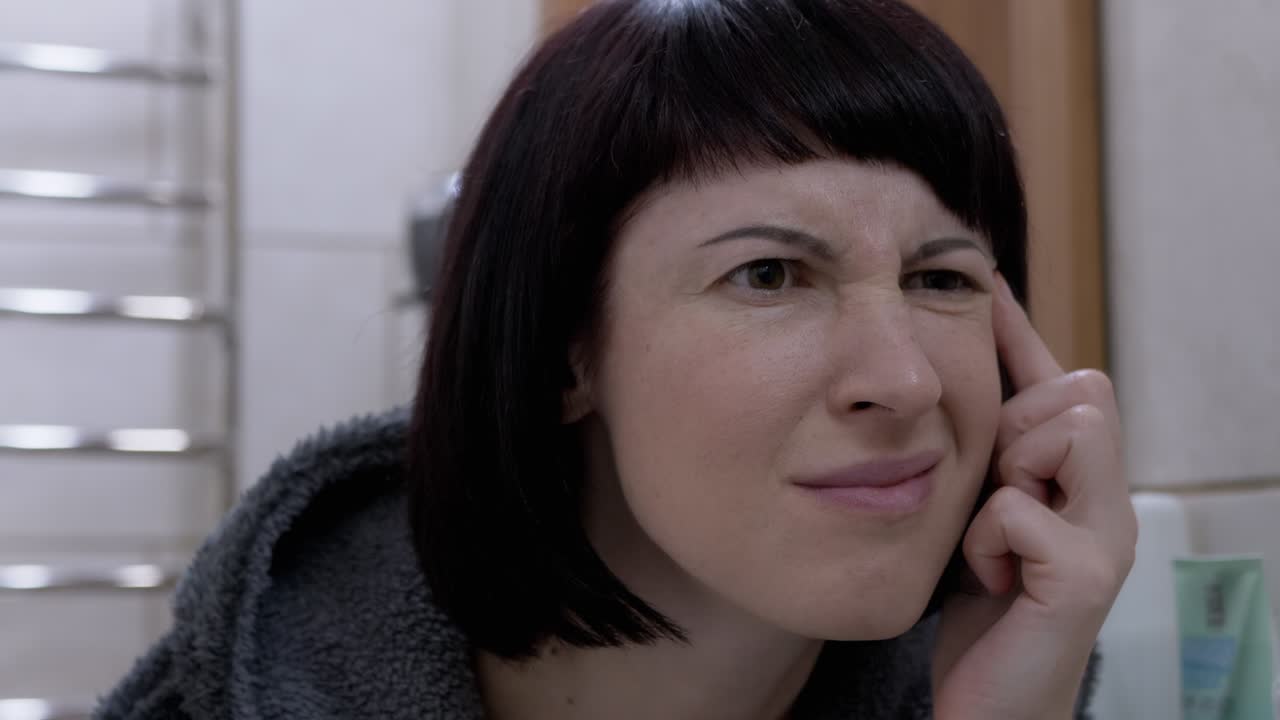 mujer mira las arrugas en el espejo, grita de horror. miedo al envejecimiento precoz de la piel