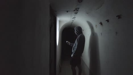 Close-view-of-a-man-with-a-flashlight-exploring-the-interiors-of-concrete-military-bunkers,-remnants-from-the-communist-era-in-Albania