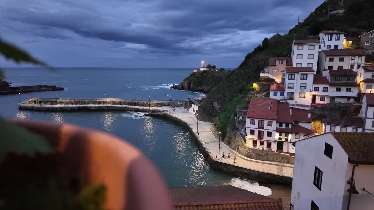 Vista al rallentatore del porto di Cudillero al crepuscolo con case illuminate, luci di Natale e il mare