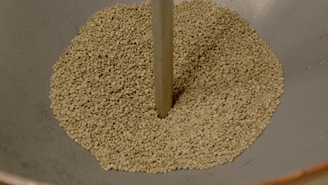 coffee beans falling into metal industrial sorter, close up slow motion shot