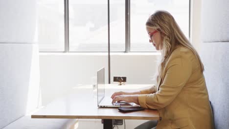 una mujer de negocios caucásica de tamaño grande usando una computadora portátil en el salón de la oficina.