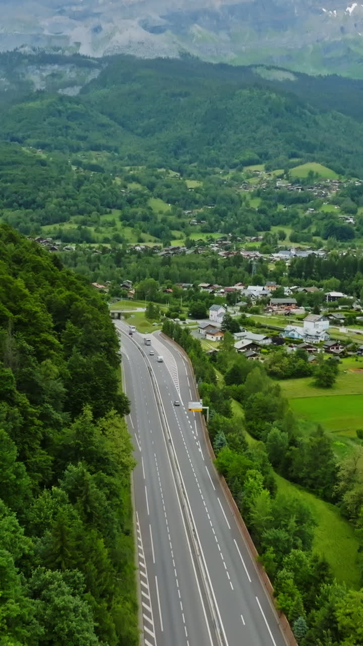 Vertical drone shot tilting over traffic on road N205 toward mountains of France