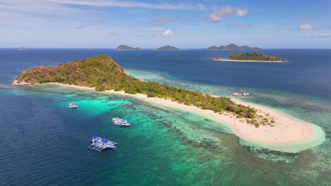 aerial view of manlihan island in linapacan, philippines, featuring turquoise waters, white sand, lush greenery, and traditional boats anchored near the coral reef surrounding the island