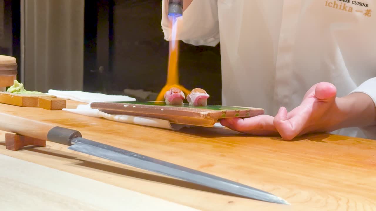 el chef usa la llama para preparar el plato de sushi.