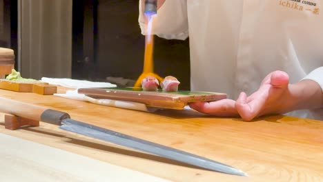 chef uses flame to prepare sushi dish