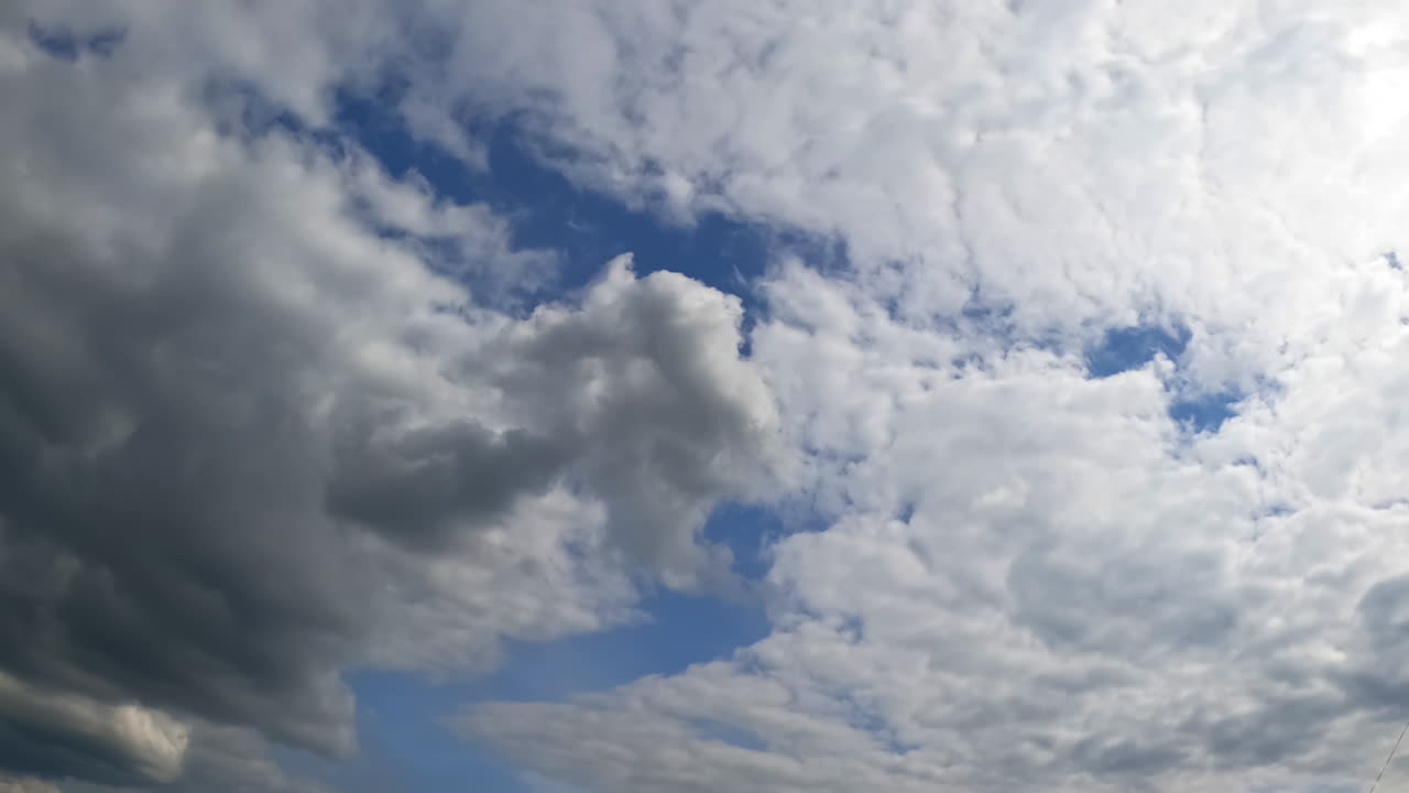 Blue skies being covered with grey clouds. Rainy cloudscape formation in the atmosphere. Low angle view. Timelapse.