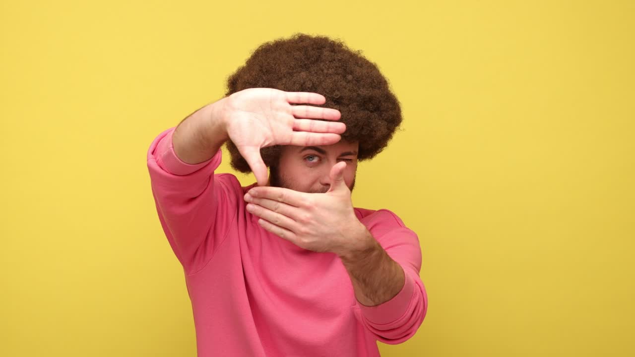 Man gesturing picture frame with hands, looking through fingers and focusing on interesting moment.
