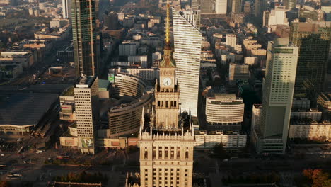 Aerial-footage-of-top-spire-of-PKIN-building-with-tower-clock.-High-angle-view-of-city-in-morning-sun.-Warsaw,-Poland