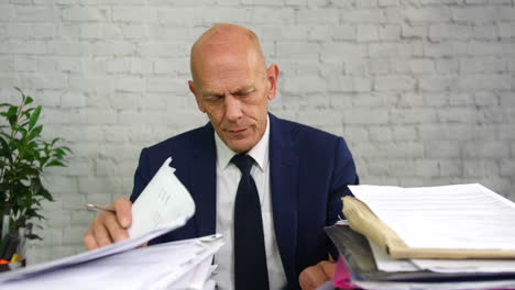 an over worked and overwhelmed businessman at work with stacks of paperwork on his desk