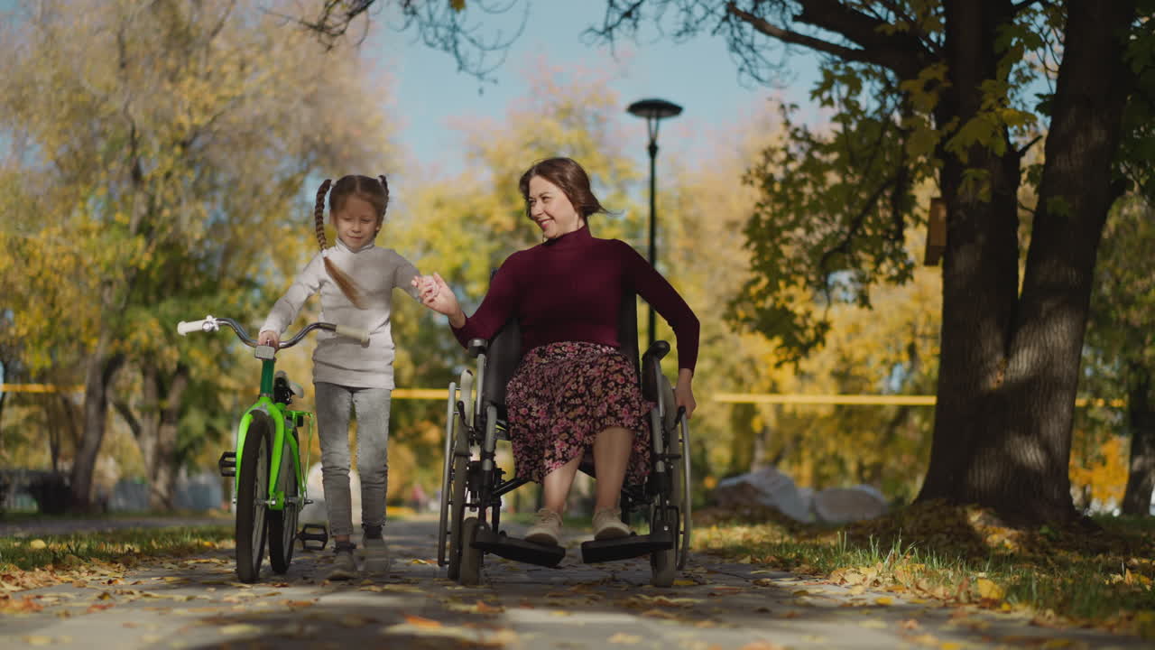 tía joven y sobrina en edad preescolar caminan en el parque unidos de manos