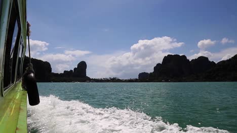 sunny day riding in a green speed boat surrounded by ocean water and rock mountains in southeast asia