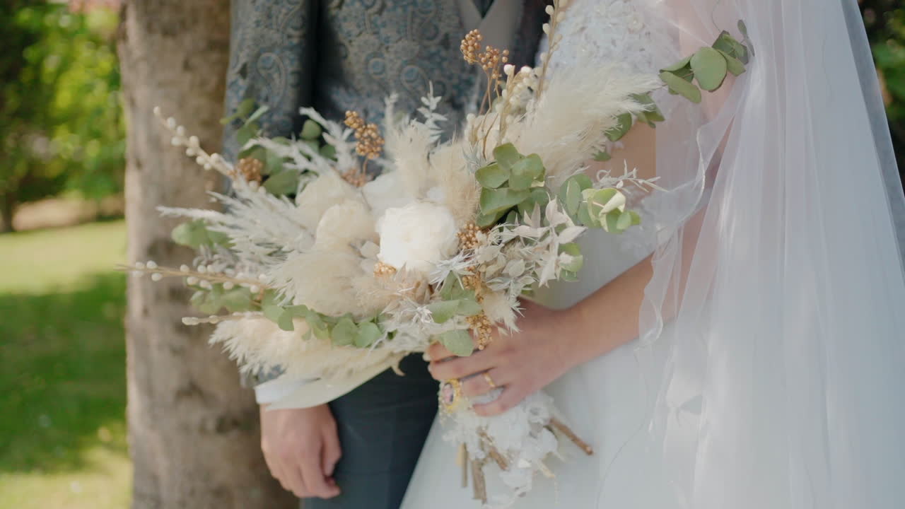Sposa che tiene un elegante bouquet accanto allo sposo, evidenziando la complessa composizione floreale