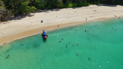 tropical beach with tourists and longtail boat