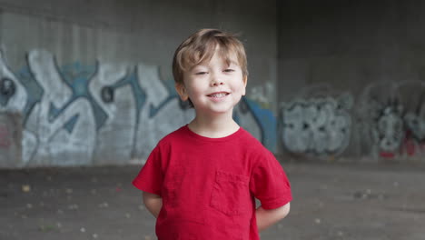 a young little boy is having fun and making funny expressions in front of camera in a red t-shirt