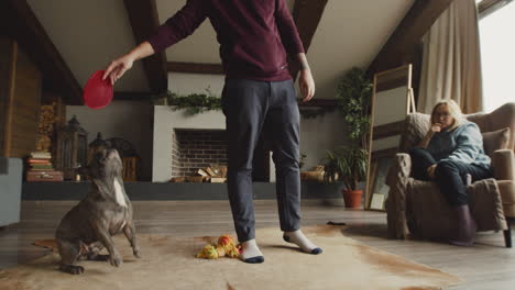 man standing while playing with her dog in the living room at home 1