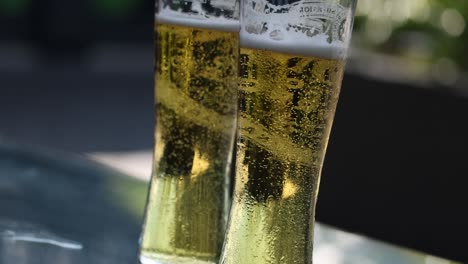 a beer glass with bubbling foam in bright daylight