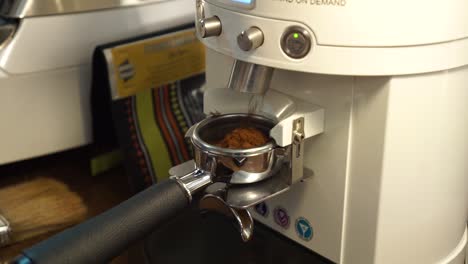 slowmo - professional female barista grinds fresh coffee beans into portafilter - close up