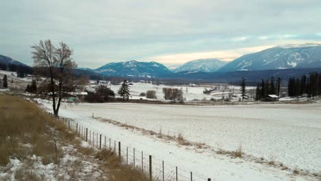 Awe-Inspiring-Tracking-Shot-of-Glistening-Mountains-with-Frosty-Grass-Farmland-in-Foreground-Near-Little-Fort,-British-Columbia,-Canada