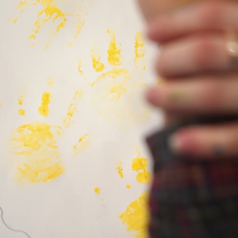 child making hand prints on paper. early childhood education. little painter.