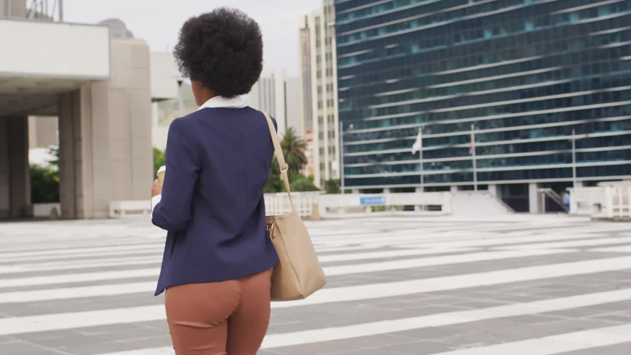 African american businesswoman holding takeaway coffee and talking on smartphone