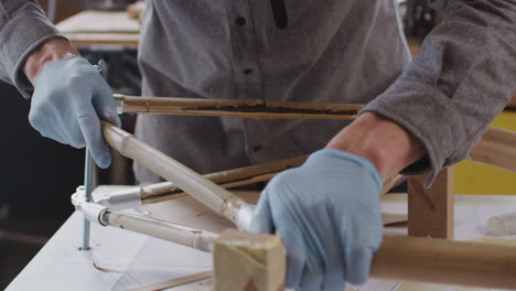 close up of male craftsman in workshop assembling hand built sustainable bamboo bicycle frame