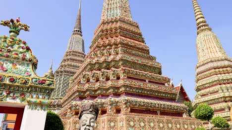 stone statue and ornate stupas at wat pho temple, bangkok