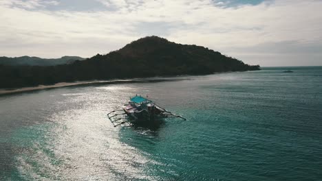 dando vueltas alrededor de un barco bangka con un reflejo del sol en el agua