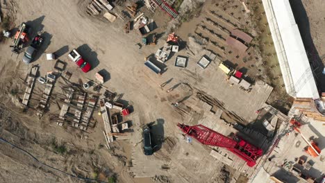 aerial top down, workers walking on construction site foundation with crawler crane