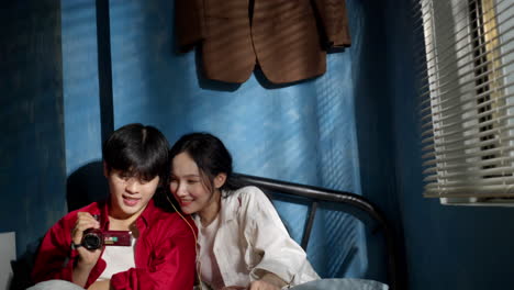 asiatic young couple watching together in their bedroom a record film clip on old vintage record video player camera