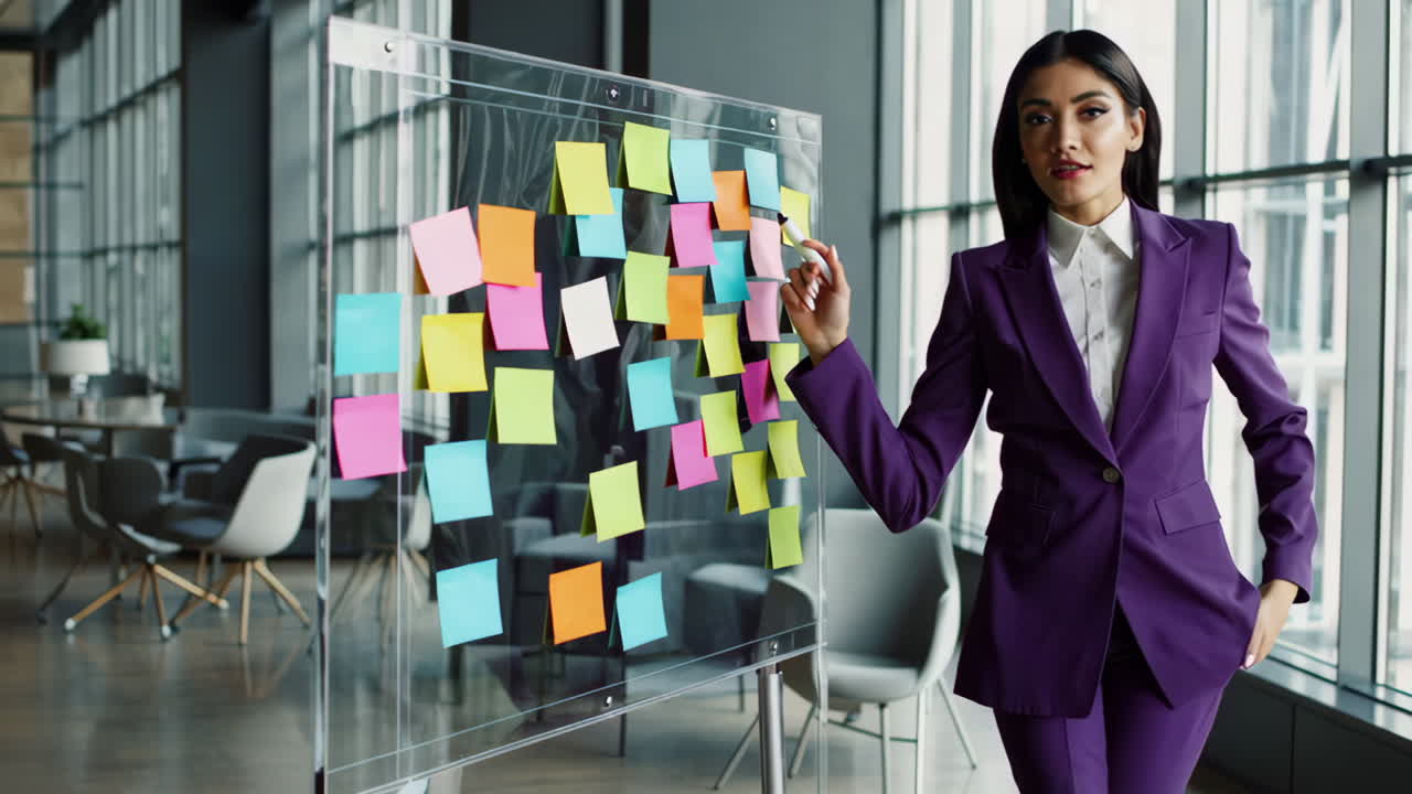 Mulher Fazendo Brainstorming com Post-its em Quadro Transparente no Escritório