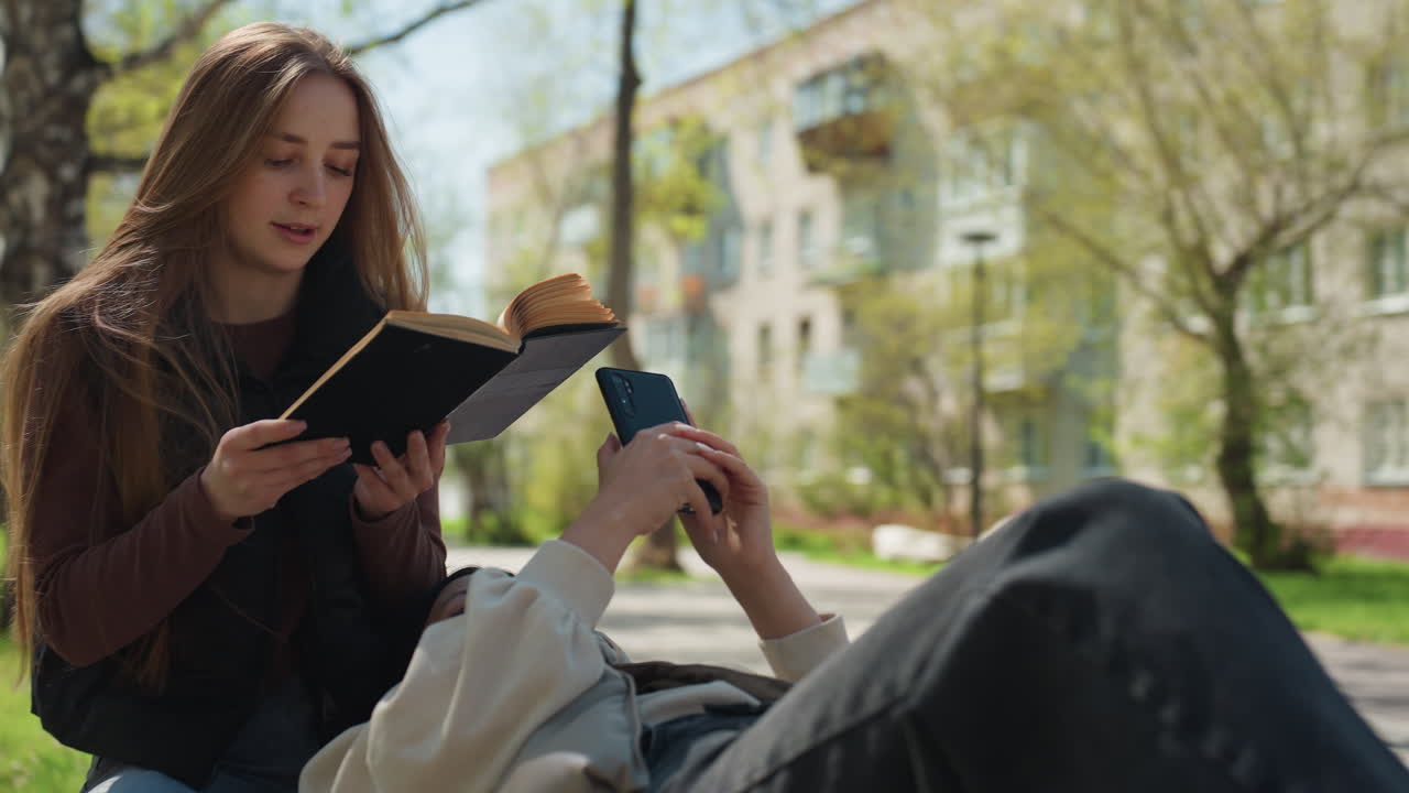Mujer informal disfrutando de su tiempo libre al aire libre, mujer descansando en el césped con un libro y un dispositivo electrónico al aire libre, mujer descansando tranquilamente en un parque con material de lectura y tecnología