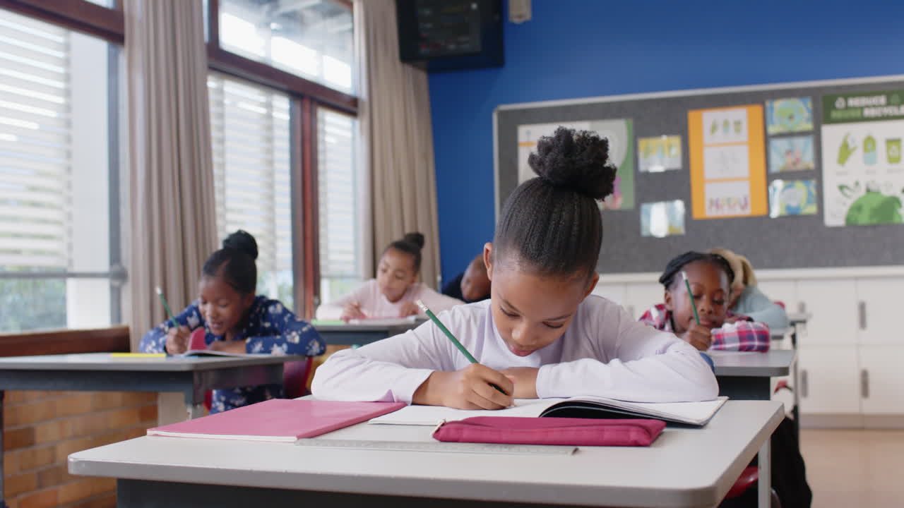 In school, children writing in notebooks at desks, concentrating on assignments