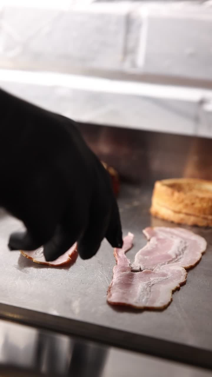 Mano che mette il bacon su una piastra calda con pane