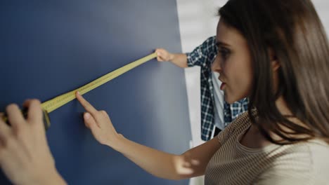 video of couple taking measure on the blue wall.