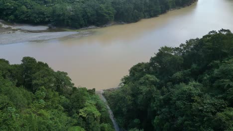 Drone-flying-over-lush-forest-with-river-in-background,-Muchas-Aguas-at-San-Cristobal-in-Dominican-Republic