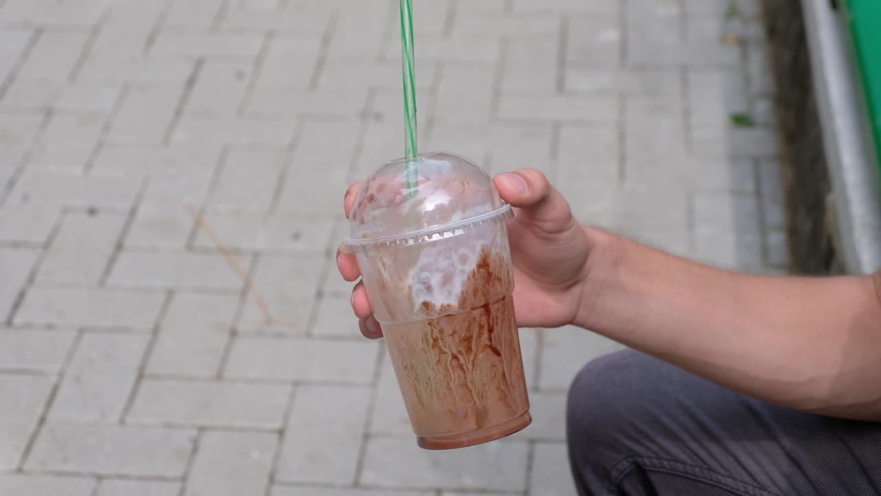 Man holding a paper milkshake cup in hands