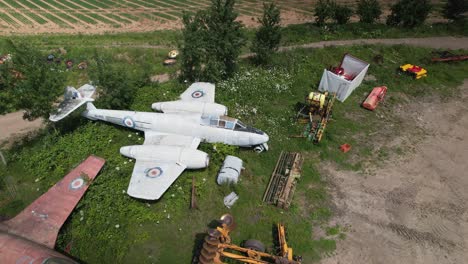 aerial orbit over the abandoned raf aircraft gloster meteor and a few other vintage jets standing on the field in england - cinematic shot