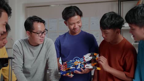 Asian Man And The Boys With A Laptop And 3D Printing Checking A Cyborg Hand At School