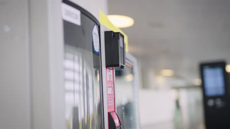 in the frame, a man's hand with a smartphone and a vending machine. the man pays for his coffee and snacks