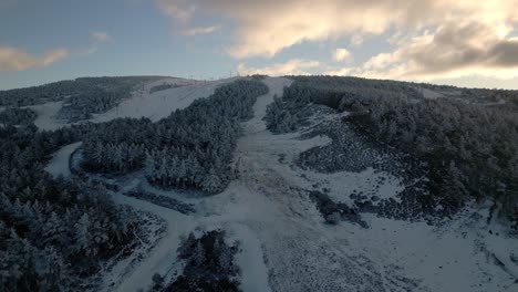 Aerial-shot-ascending-a-snowy-mountain-under-a-cloudy-sky-in-Manzaneda,-Galicia