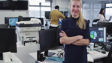 mujer cruzando los brazos y sonriendo mientras está de pie en la oficina