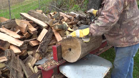 A man using a hydraulic log splitter to make firewood for the winter